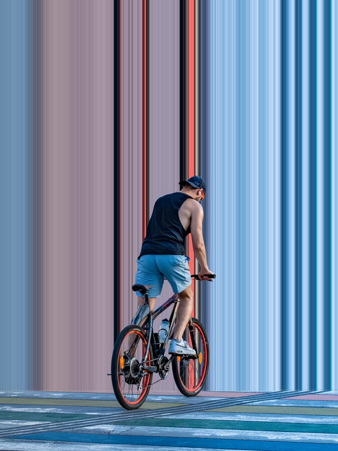 Radfahrer vor bunt gestreifter Fassade